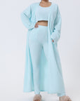 Cozy 3-piece pajama set for women, featuring a soft crop top, wide-leg pants, and a matching knee-length pullover in pastel colors.
