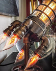 Vintage steampunk rocket lamp with intricate detailing and a glowing flame night light. This unique rocket ship lamp adds retro-futuristic charm to any room, perfect for use as a steampunk desk lamp, or stylish lighting for your bar, store, or office. Featuring high-quality craftsmanship and an E26 bulb for bright illumination, this steampunk lighting fixture enhances any space with its vintage appeal