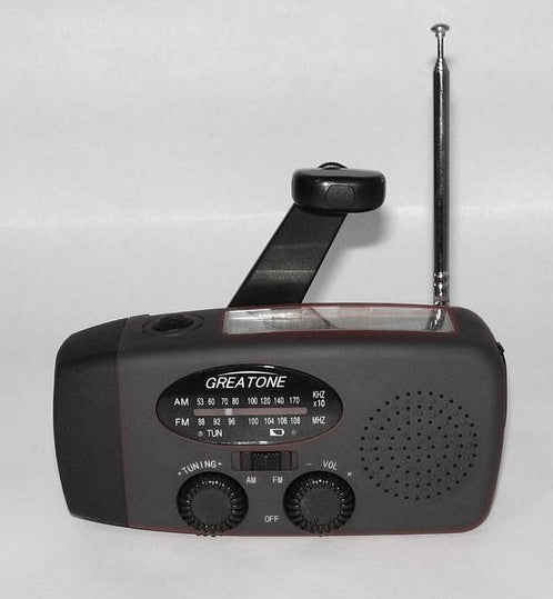 Solar hand crank radio with USB charging port, red in color. Features include a Midland Weather Alert Radio, hand crank radio flashlight, and solar charging capabilities, designed for emergency preparedness and outdoor use.
